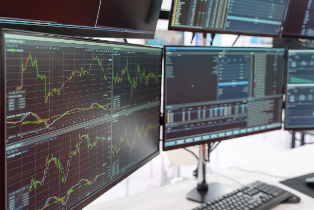 Múltiples pantallas con gráficas de mercado en tiempo real, representando el seguimiento continuo del mercado eléctrico mayorista