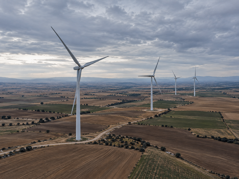 Aerogeneradores de un parque eólico sobre campos agrícolas en España bajo un cielo nublado